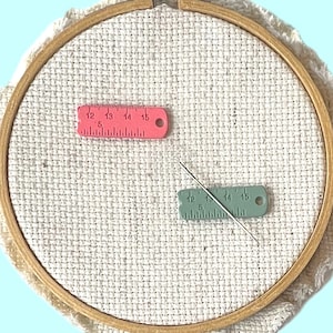 Set of 2 pink and green enamel measuring tape needle minder for cross stitch, embroidery, quilting, needlepoint, crewel, tapestry, and sewing, magnetic stitching accessory, cute pink craft tool for knitters and crocheters, durable enamel needle minder gift.