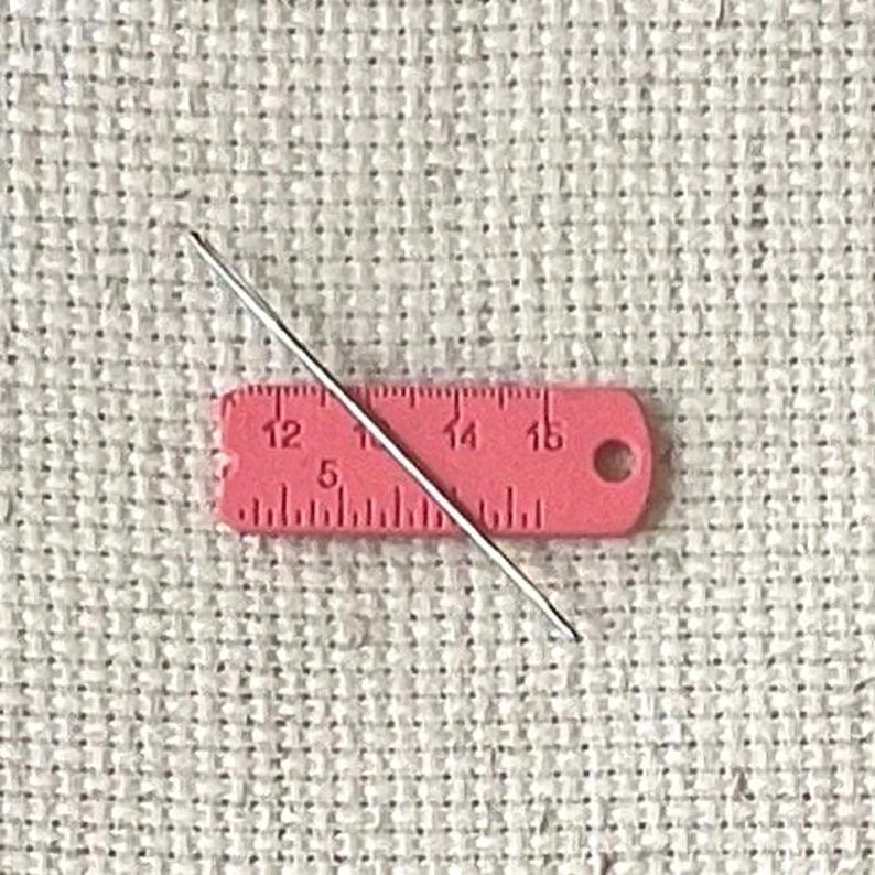 Pink enamel measuring tape needle minder for cross stitch, embroidery, quilting, needlepoint, crewel, tapestry, and sewing, magnetic stitching accessory, cute pink craft tool for knitters and crocheters, durable enamel needle minder gift.