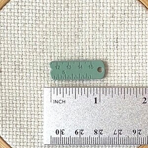 Green enamel measuring tape needle minder for cross stitch, embroidery, quilting, needlepoint, crewel, tapestry, and sewing, magnetic stitching accessory, cute pink craft tool for knitters and crocheters, durable enamel needle minder gift.