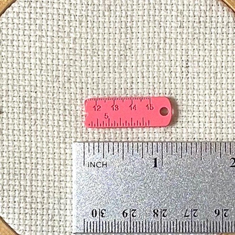 Pink enamel measuring tape needle minder for cross stitch, embroidery, quilting, needlepoint, crewel, tapestry, and sewing, magnetic stitching accessory, cute pink craft tool for knitters and crocheters, durable enamel needle minder gift.