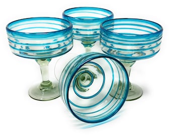 May include: Set of four blue and clear glass margarita glasses with a striped design. The glasses are hand-blown and have a unique swirl pattern.