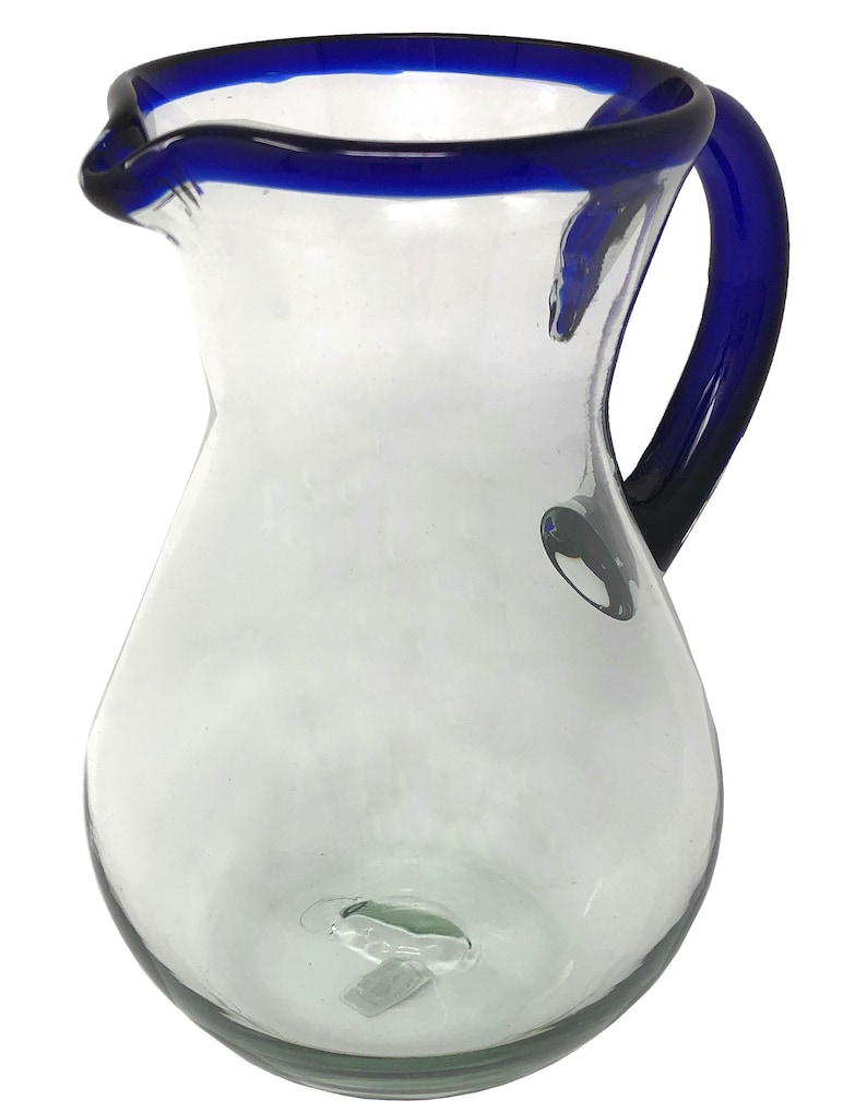 May include: A clear glass pitcher with a blue rim and handle. The pitcher has a rounded body and a wide mouth.