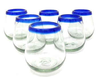 May include: Set of six clear glass tumblers with a blue rim. The glasses are round and have a wide base.