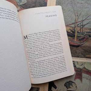 Puede incluir: Libro abierto con texto en una p&aacute;gina blanca, titulado "Cap&iacute;tulo Veintiuno: Peaking". El libro est&aacute; abierto en una p&aacute;gina de texto con una gran letra inicial. El fondo presenta una pintura de barcos.