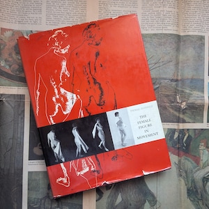 May include: A hardback book titled The Female Figure in Movement with a bright red cover featuring black line art illustrations of human silhouettes and a horizontal strip of four black and white photographs showing figures in various poses.