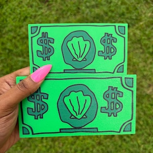 May include: Two rectangular green paper-like items featuring a black outline design of a central seashell icon flanked by dollar signs on each side. The design mimics the appearance of currency with corner accents and a bold, graphic aesthetic.
