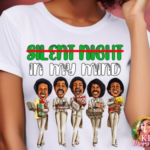 May include: White t-shirt with a green and white graphic that says "Silent Night" with a red line through it and "In My Mind" underneath. The graphic also features five cartoon men in white suits holding Christmas presents.