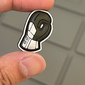 May include: A black and white rubber patch shaped like a boxing glove. The glove is outlined in black and has white details.