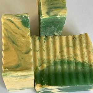 May include: Three bars of handmade soap with a green and yellow swirl pattern. The soap is made with natural ingredients and is perfect for sensitive skin.