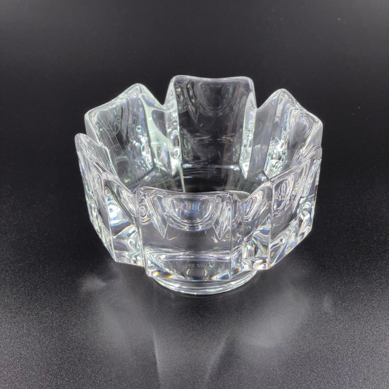 May include: A clear glass bowl with a geometric design. The bowl has a starburst shape with a flat base.