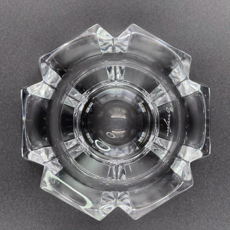 May include: A clear glass bowl with a starburst design and a raised center. The bowl is signed "Orrefors" on the bottom.