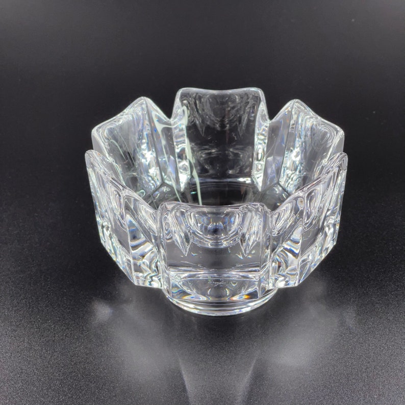 May include: A clear glass bowl with a geometric design. The bowl has a starburst shape with multiple facets.