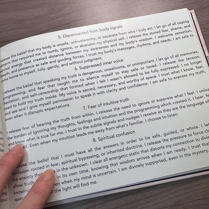 May include: An open book with text discussing body signals, inner voice, and intuitive truth. The pages are white with black text. A hand points to the text.