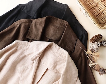 May include: Three linen blazers in black, brown, and beige are arranged in a layered composition. The blazers have classic lapel collars and long sleeves. The image is shot from above, showcasing the textures and colors of the garments.