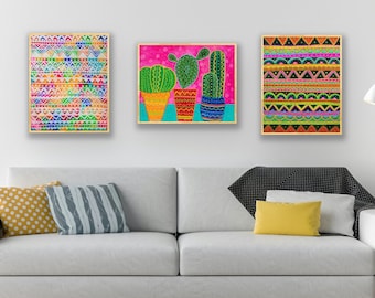 May include: Three framed prints with colorful geometric patterns and a cactus illustration. The prints are hung on a white wall above a white couch with yellow and gray pillows.