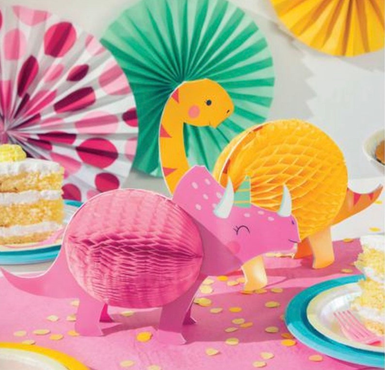 Op de afbeelding: Roze, gele en groene papieren dinosaurusdecoraties voor een feestje. De dinosaurussen zijn gemaakt van honingraatpapier en hebben een 3D-effect.