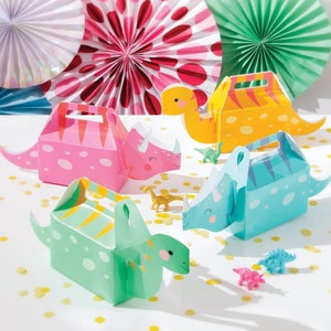 Op de afbeelding: Vier kleurrijke dinosaurusvormige party-favourdozen met handvatten. De dozen zijn roze, blauw, groen en geel met witte stippen. Elke doos heeft een ander dinosaurusontwerp.