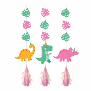 Op de afbeelding: Drie dinosaurus-party hangdecoraties met groene bladeren en roze kwastjes. De dinosaurussen zijn een groene T-Rex, een gele brachiosaurus en een roze triceratops.