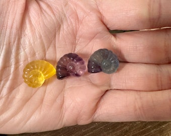 May include: Three small, colorful ammonite-shaped crystal specimens. The ammonites are yellow, purple, and blue.