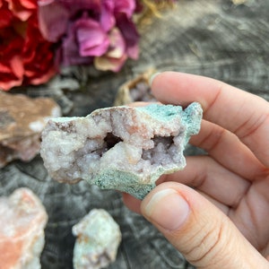 May include: A cluster of pink amethyst crystals with a natural, rough exterior. The crystals are clustered together in a small, irregular shape. The amethyst is a light pink color and has a translucent appearance.