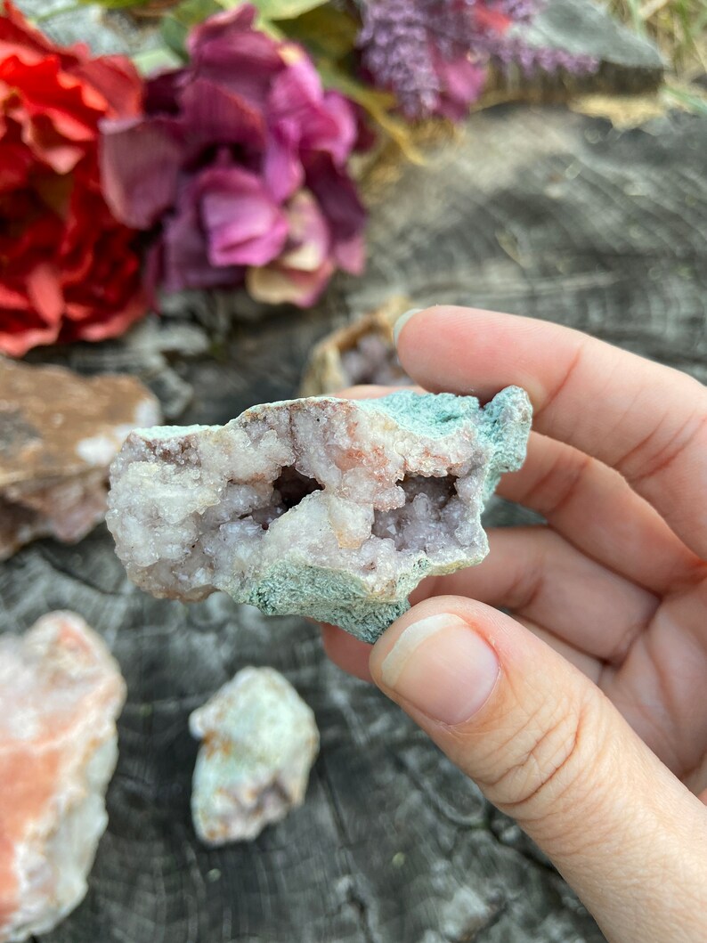 May include: A cluster of pink amethyst crystals with a natural, rough exterior. The crystals are clustered together in a small, irregular shape. The amethyst is a light pink color and has a translucent appearance.
