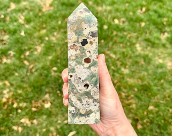May include: A green, brown, and white agate tower with a pointed top. The tower is about 5 inches tall and has a unique, swirling pattern.