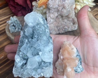 Può includere: Tre gruppi di cristalli, uno è trasparente, blu chiaro, uno è rosa chiaro e l'altro è bianco e rosa chiaro.