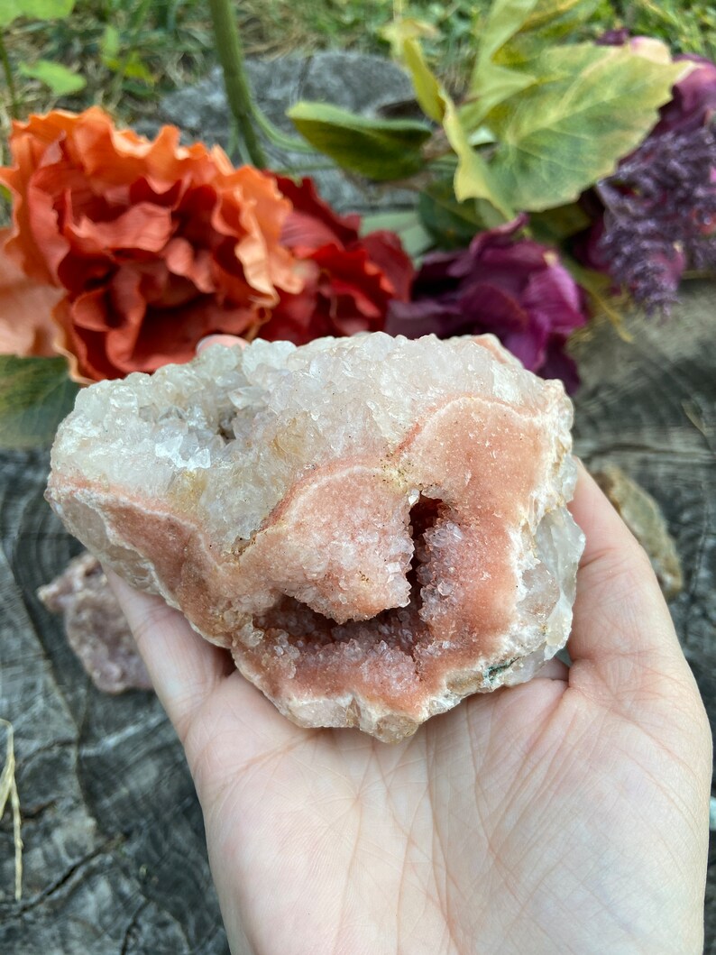 May include: A pink and white crystal cluster with a large, open cavity. The crystal is rough and has a natural, organic shape.
