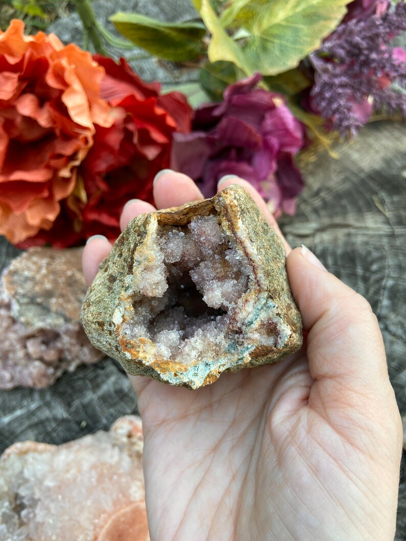 May include: A geode with a rough exterior and a hollow interior filled with light purple crystals.