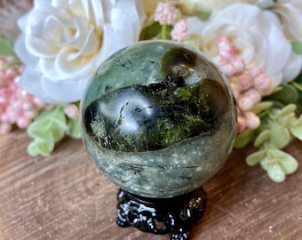 May include: A green and black sphere crystal ball on a black stand. The sphere is polished and has a swirling pattern of green and black.
