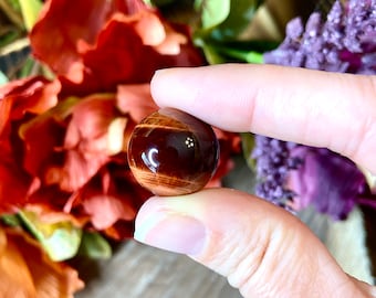 May include: A round, brown and red tiger's eye gemstone sphere.