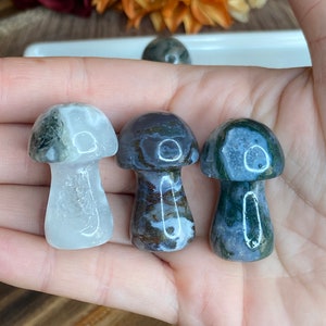 May include: Three agate mushroom shaped crystal carvings. One is white with green and gray swirls, one is gray with brown and white swirls, and one is gray with green and white swirls.