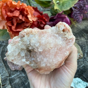 May include: A large, pink, and white crystal cluster with a rough, natural texture. The crystal is covered in small, white crystals.