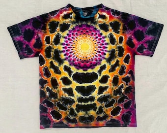 May include: A short-sleeve t-shirt featuring a vibrant tie-dye pattern with a central yellow sunburst mandala design surrounded by concentric rings of magenta, orange, and black organic shapes that extend across the entire fabric surface.