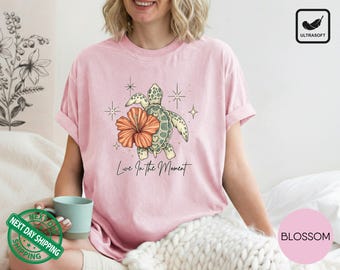Camiseta Comfort Colors con estampado de tortugas marinas, camiseta con estampado de hibiscos tropicales, camiseta con el lema "Vive el momento".