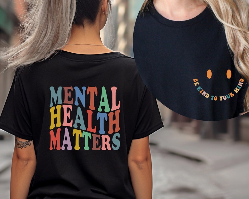 May include: Two black t-shirts with colorful text. The front shirt says "Be Kind to Your Mind" in a rainbow arc with a smiley face. The back shirt says "Mental Health Matters" in colorful block letters.