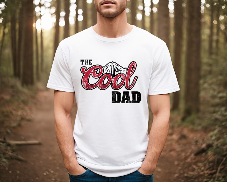 May include: White t-shirt with a red graphic that says "The Cool Dad" with a mountain design.