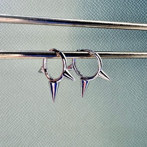 May include: A pair of silver hoop earrings with three sharp points on each hoop.
