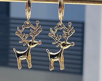 May include: A pair of gold hoop earrings with a reindeer charm. The reindeer is detailed with small rhinestones.
