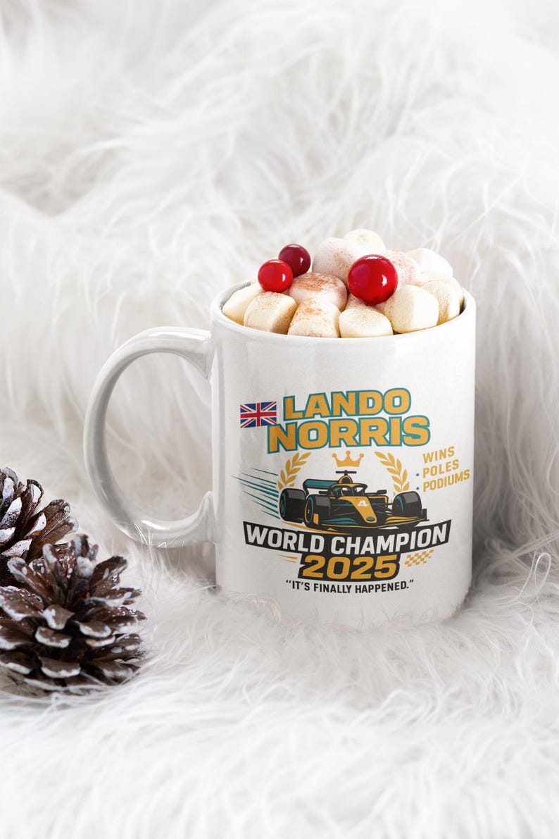 Op de afbeelding: Witte keramische mok gevuld met marshmallows en rode bessen. De mok heeft een ontwerp met de tekst "LANDO NORRIS WORLD CHAMPION 2025" en een Formule 1 raceauto-afbeelding. De mok heeft een handvat.