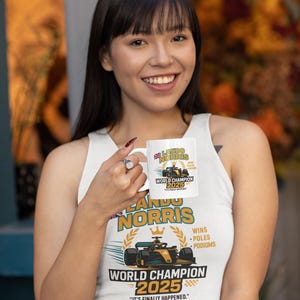 Op de afbeelding: Witte keramische mok met een Formule 1-raceauto-ontwerp en de tekst "LANDO NORRIS WORLD CHAMPION 2025". De mok bevat ook de tekst "WINS, POLES, PODIUMS" en "IT'S FINALLY HAPPENED."