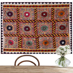 May include: A colorful patchwork wall hanging with a geometric design featuring embroidered stars and mirrored accents. The fabric is a mix of red, yellow, blue, and green.