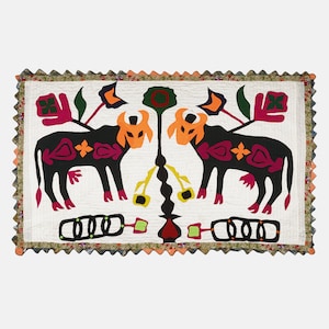 May include: A white cotton quilt with a colorful applique design. The design features two black cows with pink, red, and yellow accents, and a central motif of a stylized tree with green leaves and a red heart.