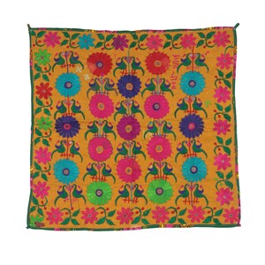 Può includere: Un quadrato di tessuto giallo con un motivo ripetuto di fiori e uccelli ricamati. I fiori sono in tonalità di rosa, blu, verde e viola. Gli uccelli sono verdi e hanno gli occhi neri.