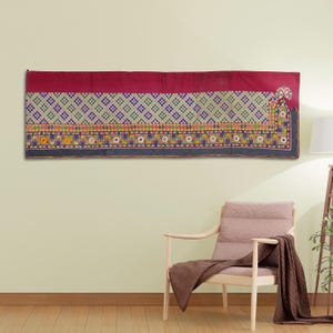 Puede incluir: Un tapiz de pared colorido con un patrón geométrico y bordados intrincados. El tapiz está hecho de tela y presenta una variedad de colores, incluyendo rojo, azul, verde, amarillo y blanco.