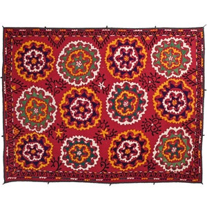 K&ouml;nnte beinhalten: Ein roter Wandbehang aus Stoff mit einem sich wiederholenden Muster aus bunten gestickten Blumen. Die Blumen sind von einem schwarzen und wei&szlig;en geometrischen Muster umgeben.