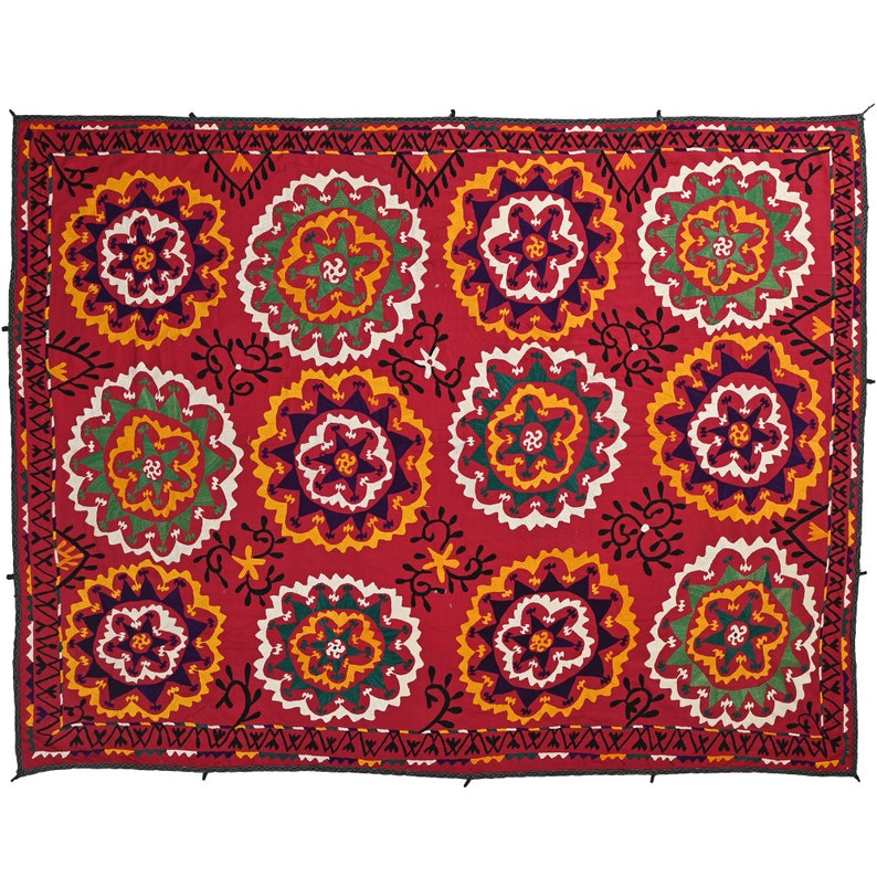 K&ouml;nnte beinhalten: Ein roter Wandbehang aus Stoff mit einem sich wiederholenden Muster aus bunten gestickten Blumen. Die Blumen sind von einem schwarzen und wei&szlig;en geometrischen Muster umgeben.