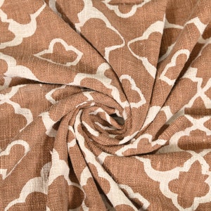 May include: Brown fabric with a white geometric pattern. The fabric is folded and twisted, showing the texture of the material.