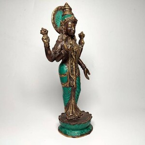 May include: A bronze statue of a Hindu goddess with four arms, wearing a green and gold sari. The statue is standing on a lotus base.