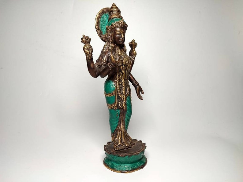 May include: A bronze statue of a Hindu goddess with four arms, wearing a green and gold sari. The statue is standing on a lotus base.